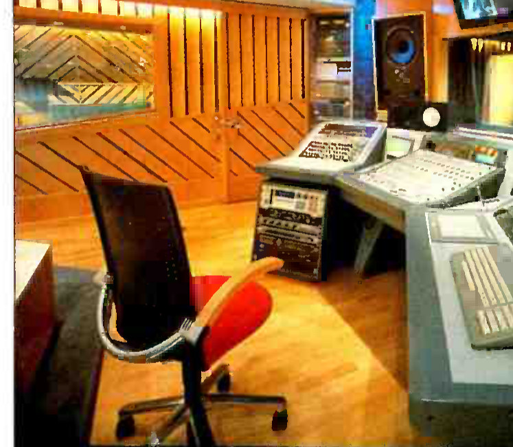 The control room at DUY Studios in Barcelona in 1993: a mixing desk with two screens and a keyboard, a rack of outboard gear, a monitor speaker on the wall, and a wood-panelled live room through the glass.